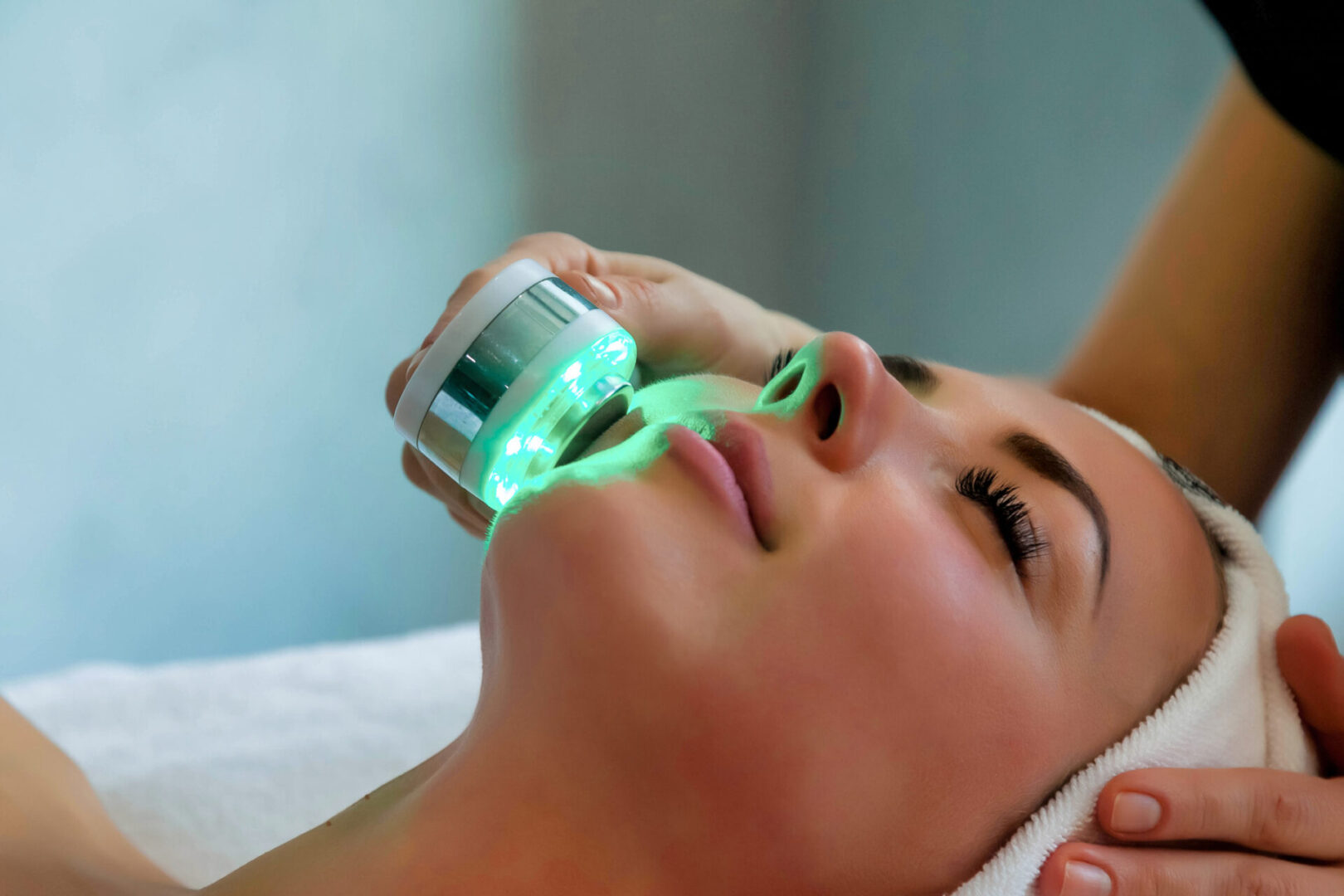 Beautician doing led light therapy to woman in SPA salon, facial phototherapy for skin pore cleaning. Anti-aging treatments and photo rejuvenation procedure. Lady getting face therapy in SPA resort